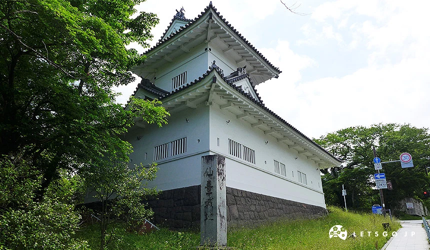 仙台城大手門脇櫓與石垣,白色牆面的復元建築佇立於綠意盎然的樹木與道路旁