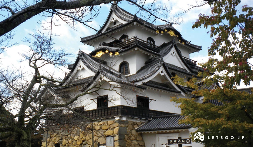 彦根城天守閣正面,白色外牆與黑色木格窗,石垣基座前有遊客參觀