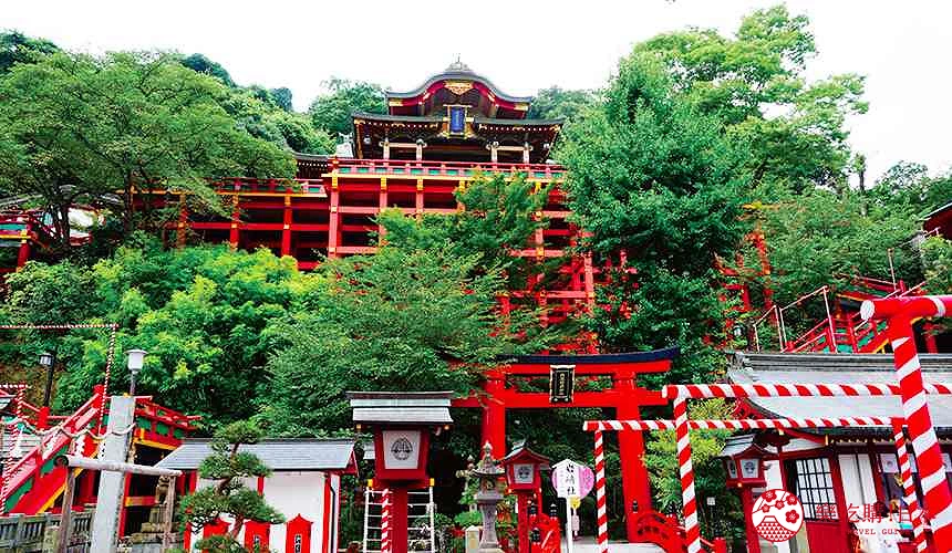 祐德稻荷神社朱紅色鳥居與木造本殿,階梯蜿蜒穿過綠樹環抱的山坡,營造莊嚴氛圍