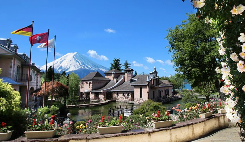 河口湖音樂森林美術館歐風庭園景色,前景花園與小橋流水環繞,遠方可見富士山