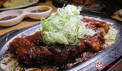 鐵盤上有豬排,上面灑有大量綠色蔥花