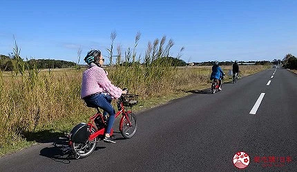 在柏油路上騎著紅色自行車的女性