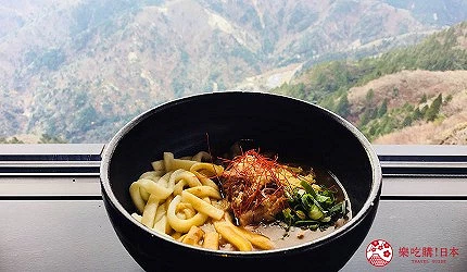 盛裝在黑色碗公的咖哩烏龍麵,背景為遠方山景