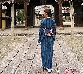 穿著藍色和服,背對畫面的女性,背景為神社