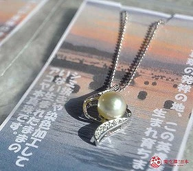 項鍊放在印刷品上,吊墜有白色珍珠和閃亮裝飾