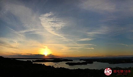 黃色太陽在水面上方,天空有雲朵,水中有島嶼