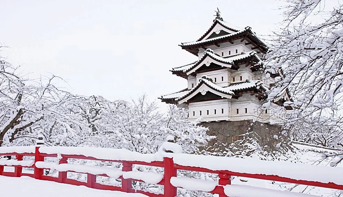 被白雪覆蓋的日本城堡,旁邊有一座紅橋
