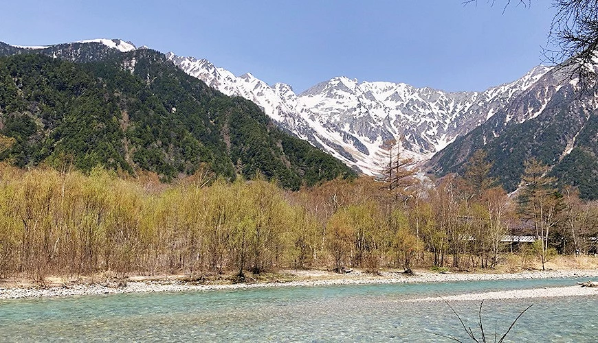冬天上高地群峰被白雪覆蓋的景觀前景是樹群與溪流