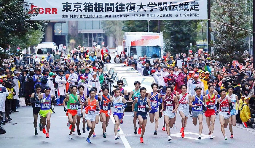 多支大學生隊伍在箱根駅伝比賽起點同時起跑,兩側可見大量觀眾與媒體,展現日本新年期間的熱門運動賽事景象