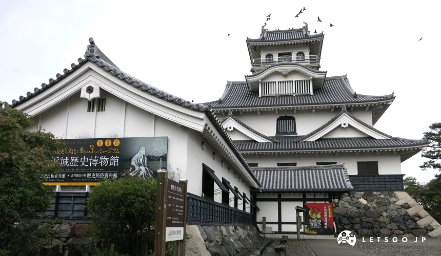 長浜城歷史博物館外觀,白牆黑瓦多層天守閣,前方立有館名看板,上方可見數隻飛鳥