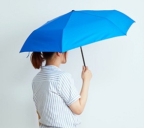 女性撐藍色雨傘側身示範,呈現遮雨範圍與實際使用情境