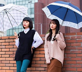 兩名女性撐深藍色雨傘站在磚牆前,示範日常使用情境