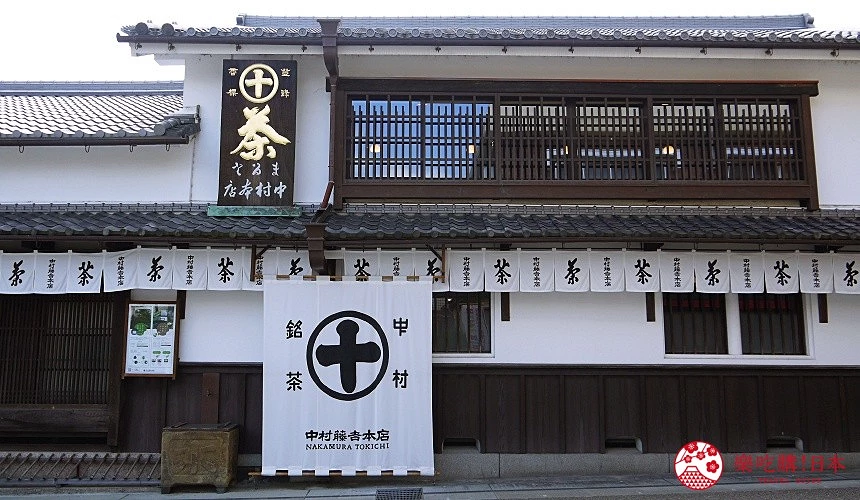 白色日式町屋外觀,門前掛著印有「茶」字樣的暖簾與「中村銘茶」招牌,二樓為深色木格柵窗。