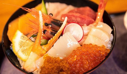 海鮮丼盛裝鮭魚卵、干貝、蟹腳、蝦子與生魚片