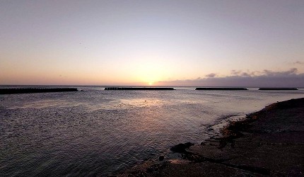 海邊日出景色,水平線上有防波堤