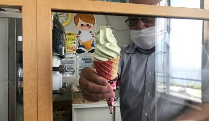 戴口罩的店員透過窗口遞出一支霜淇淋