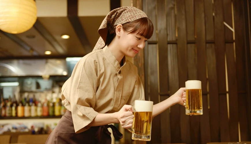 一個女服務生正將兩杯啤酒放到桌上