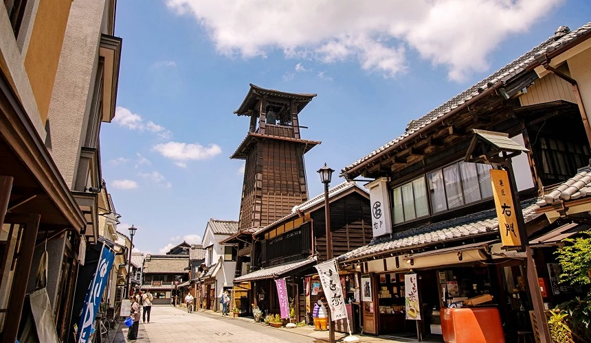 川越一番街商店街,中央矗立木造時之鐘鐘樓,兩側為傳統日式建築與商店,寫有「右門」等看板文字