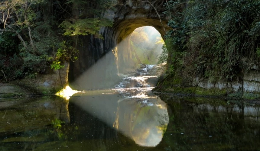拱形岩洞映照晨光水面,形成心形光影景象。