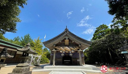 一座神社，建築前方有兩側的石像，周圍被綠樹環繞和藍天