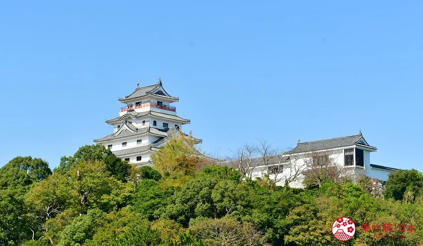 白色唐津城天守閣坐落於綠樹覆蓋的山丘上