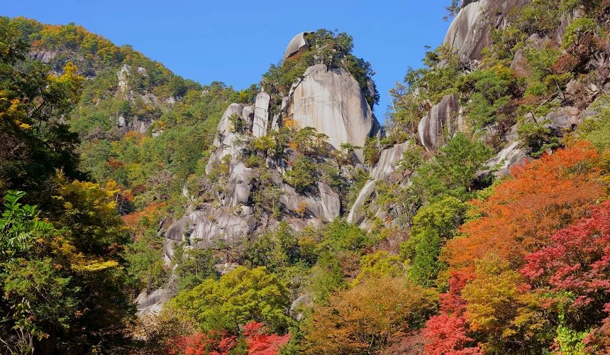 昇仙峽秋季峽谷景觀,巨大的岩壁與奇岩聳立其間,山林染上紅葉與黃葉