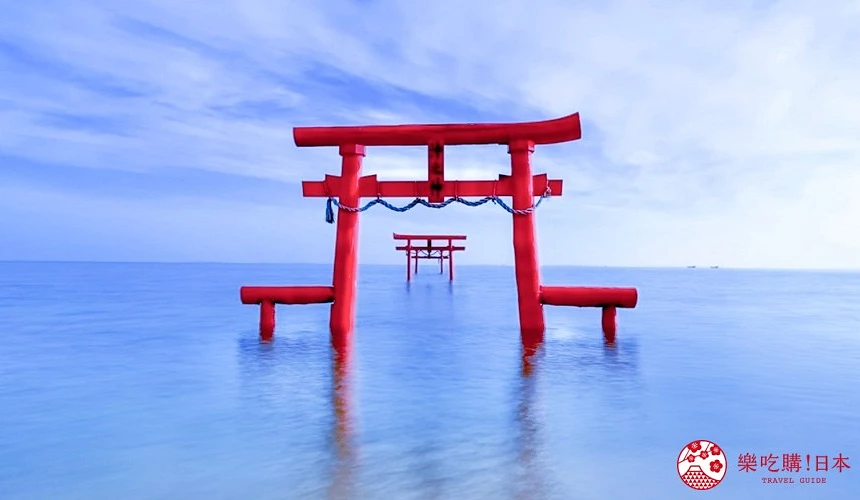 湛藍海水中矗立著鮮紅鳥居,水面映出淡淡倒影,遠方隱約可見第二座鳥居,背景為白雲點綴的海天一線。