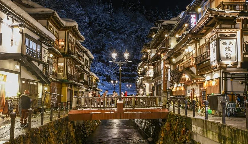 銀山溫泉夜景,河道兩側木造旅館與橋上行人的街景