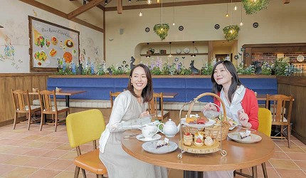 兩名女性在彼得兔咖啡廳內用餐,桌上擺放英式下午茶點與茶壺,室內裝潢溫馨明亮