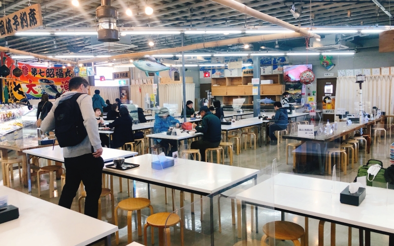 松島魚市場室內用餐區的多張餐桌，有人坐著用餐
