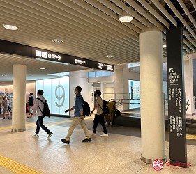室內地下街出口處,天花板掛有「9番出口」標示,人群正走動