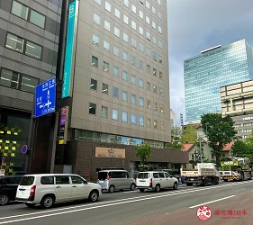 札街道一側的高樓建築外觀,前方停有多輛白色與黃色車輛