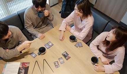 四位旅客坐在MIMARU大阪 難波STATION客房的餐桌旁玩桌遊、喝飲品
