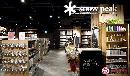 寫著snowpeak的店內木頭貨架擺放了露營用的商品
