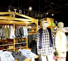 木頭貨架上擺放了休閒服飾，旁邊有兩個人型穿著服飾