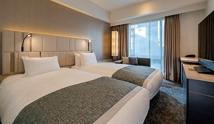 大和ROYNET飯店東京京橋PREMIER的雙人客房，房間採用現代簡約設計，配有雙人床、辦公桌椅和大片窗戶，室內裝潢以中性色調為
