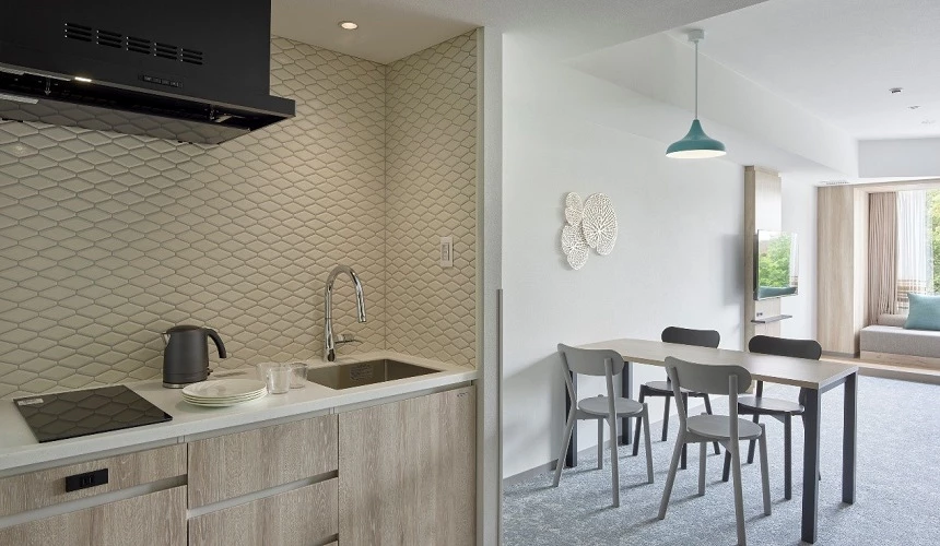 &Here TOKYO UENO的Family Room廚房區域，配備現代化廚具設備，包含流理台、餐桌椅和吊燈，空間設計簡潔實用