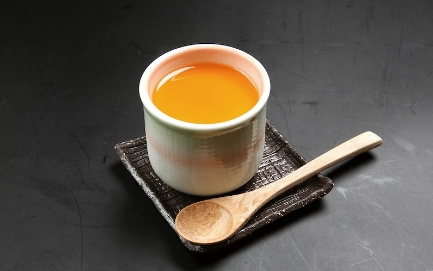 擺在黑色桌面上的一杯布丁，放有一支木湯匙