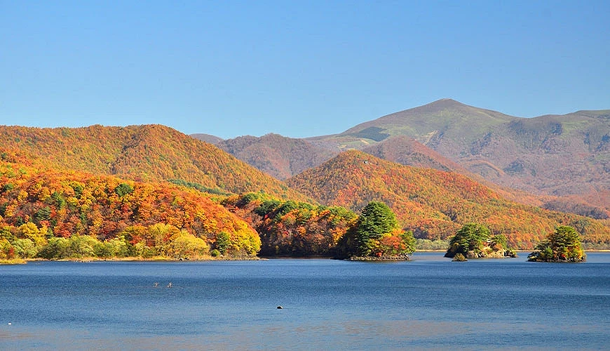 福島裏磐梯的秋日景色,湖水倒映紅葉山巒,遠方磐梯山壯麗矗立