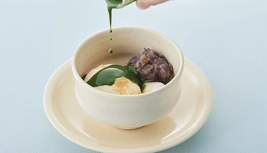一杯白色瓷杯裡裝著和式甜點並淋上抹茶醬