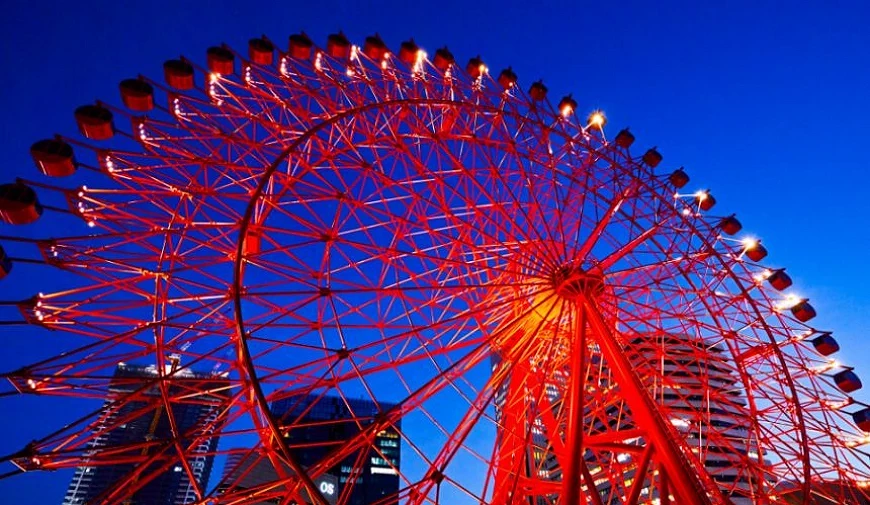 夜晚的 HEP FIVE 紅色摩天輪從低角度拍攝,輪架亮起燈光,背景可見梅田高樓的夜景輪廓
