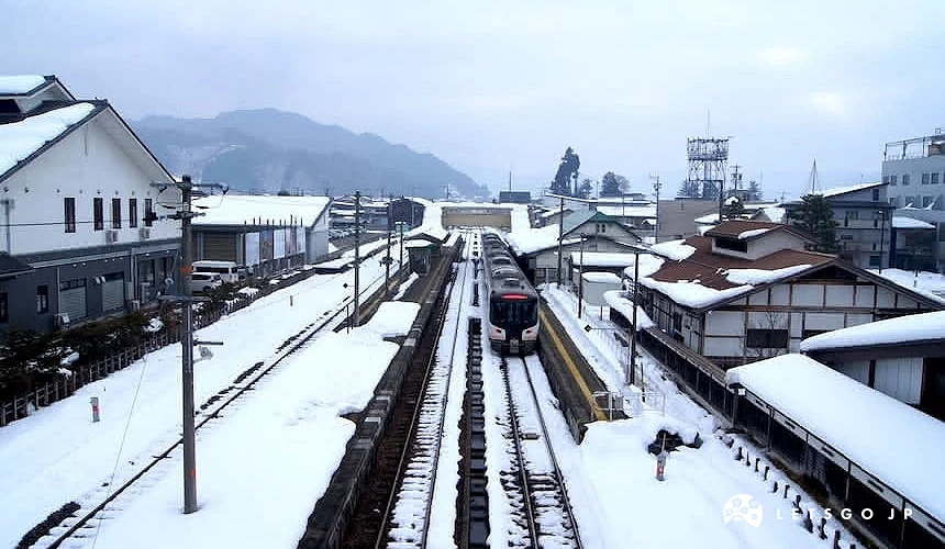 積雪覆蓋的飛驒古川車站景色,列車緩緩進站,月台與屋頂鋪滿白雪,呈現寧靜寒冬中的飛驒地區車站風光