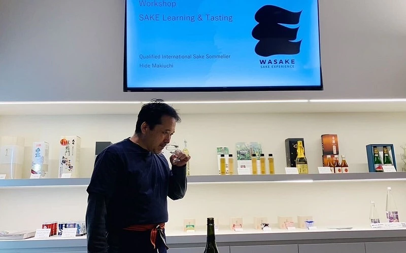 講師在清酒體驗店進行聞香示範,後方展示清酒商品