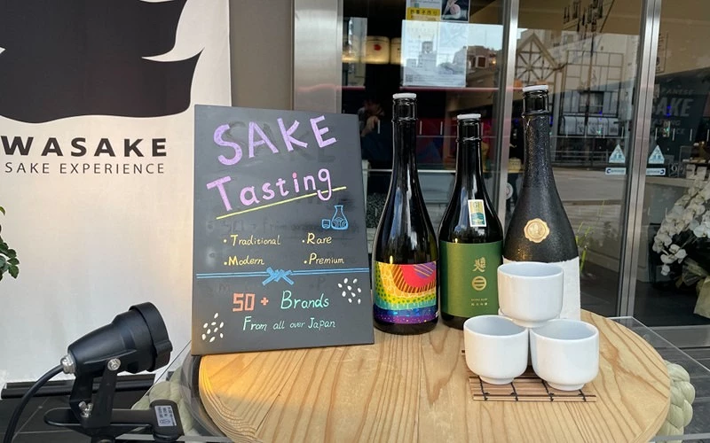 店門口展示清酒與試飲看板,標示 Sake Tasting 與品牌數量