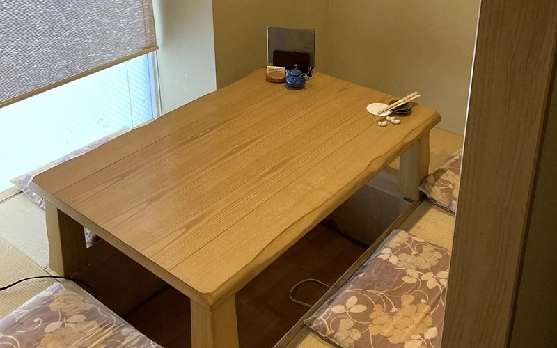 木質餐桌擺放茶具與餐具旁有坐墊