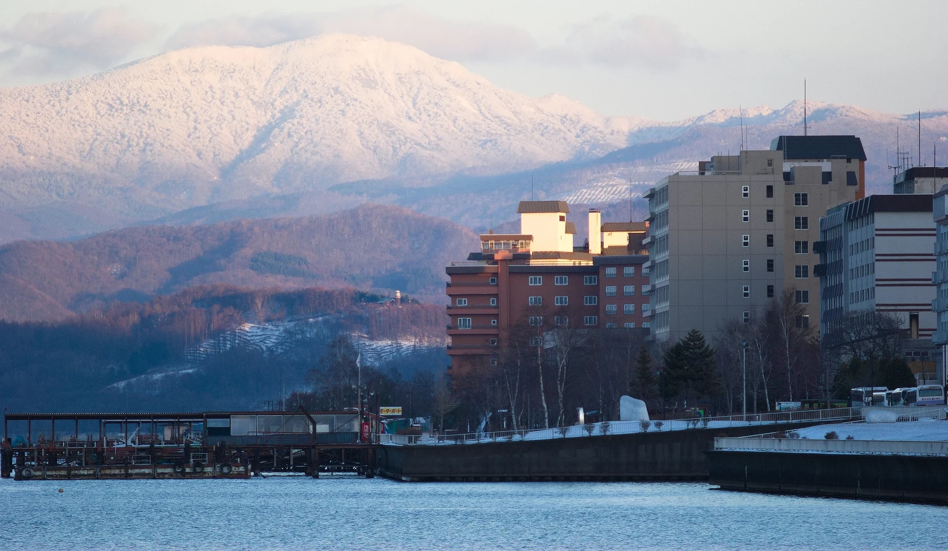 洞爺湖溫泉街冬季景色,湖畔飯店林立,背景為覆雪山巒與冬日天空