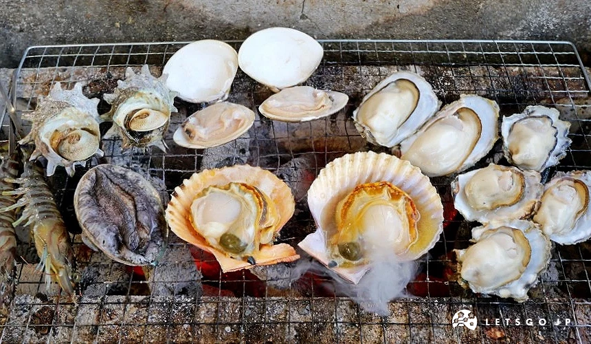 各種貝類海鮮平鋪在炭火爐上碳烤