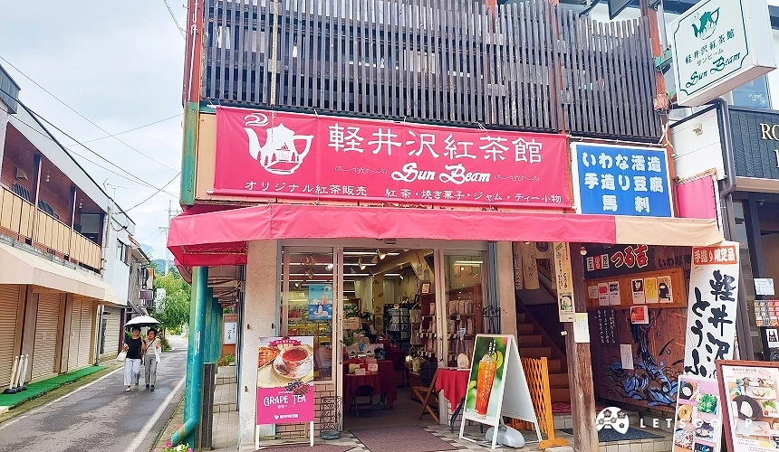 位於舊輕井澤銀座通商店街的輕井澤紅茶館 (Sun Beam) 店面,鮮紅色的招牌與遮雨棚非常奪目,門口擺放著精緻的下午茶推薦海報,店內專賣各式原創紅茶與茶包組合