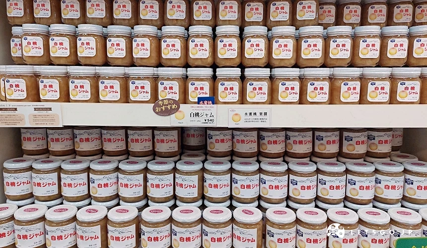 澤屋果醬 (SAWAYA JAM) 店內整齊陳列的白桃果醬貨架,透明玻璃瓶裝著粉橘色的手工果醬,上方貼有「季節推薦」標示