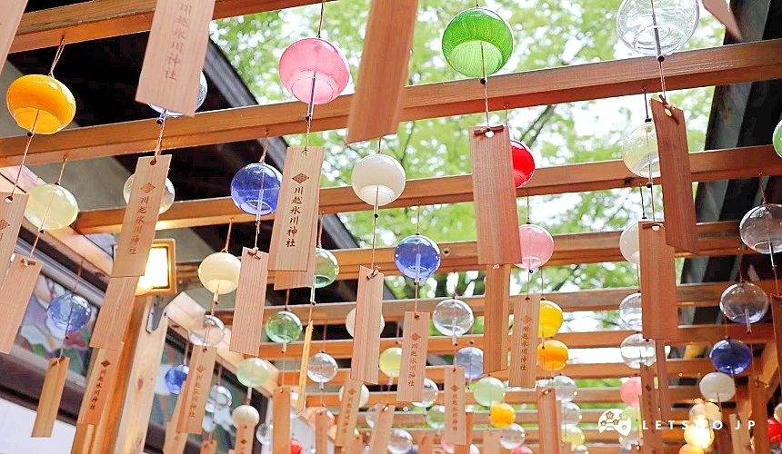 川越氷川神社內懸掛多排彩色玻璃風鈴與木製繪馬的戶外廊架